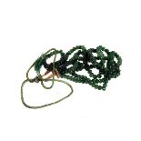 An emerald bead three strand necklace,  composed of graduated melon cut beads, to a silk cord tie