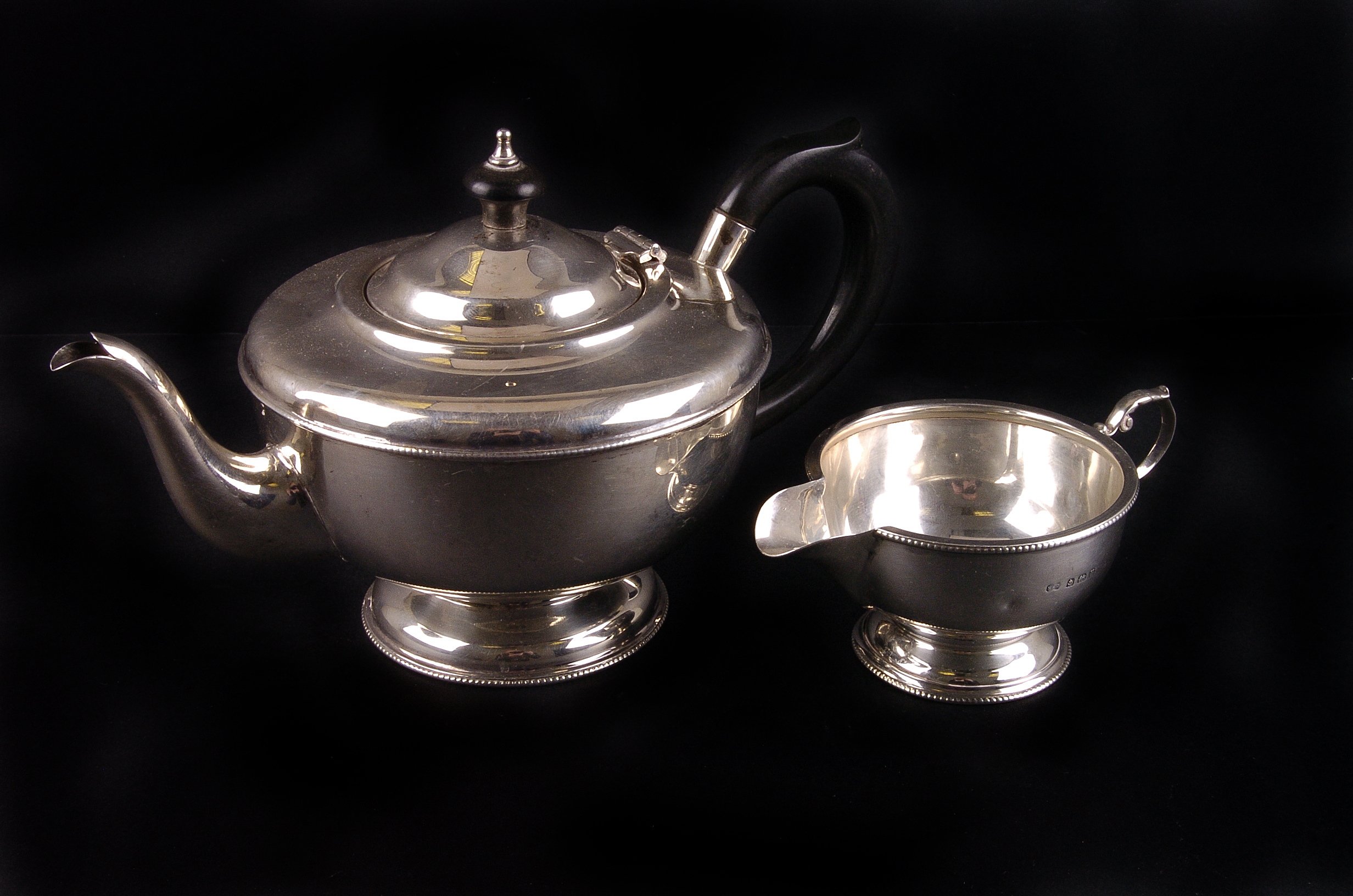 A George V silver circular teapot by Marson & Jones,  Birmingham 1932, with ebonised hoop handle and