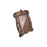 An Edwardian silver photograph frame by William Neale, Chester 1903, the shaped rectangular frame