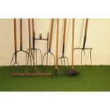A group of ten antique and vintage farm long handled tools, including various pitch forks with