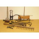 A collection of antique and vintage farm hand tools, including a thatcher's hook, a wooden yoke, a