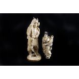 A c.1920 Tokyo school ivory carving of a samurai, together with a figure of a geisha holding aloft a