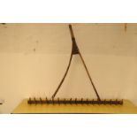 A large antique hand held rake, having split shaft and comb head, approx. 152cm wide