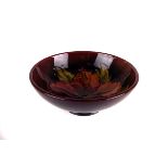 A 20th century Moorcroft bowl, with brick red ground, and flower to the centre, with impressed