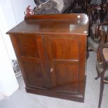 An Edwardian mahogany hall cupboard,  with panel doors enclosing adjustable shelves,  on a plinth