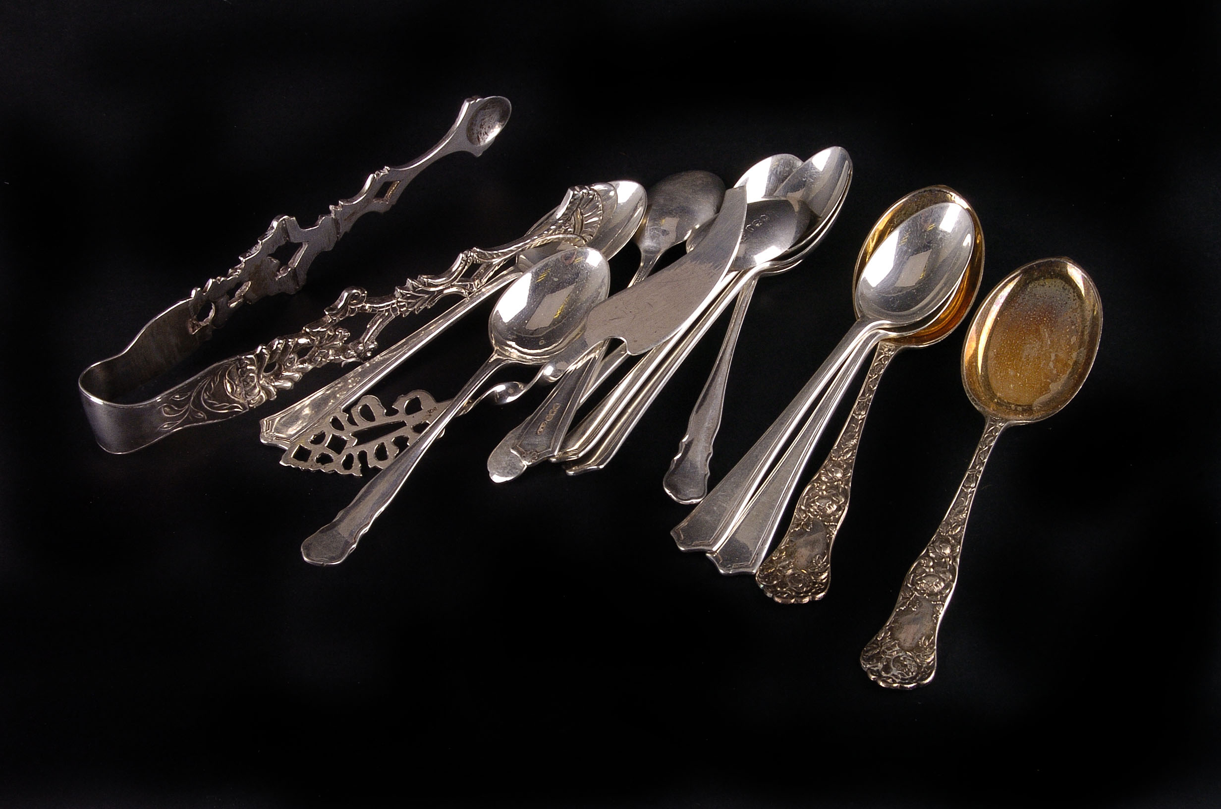 A small collection of silver tea spoons, fruit knives, and silver handled pistol grip cake knives