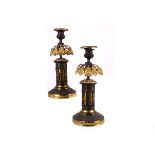 A pair of Regency bronze candleholders, the circular spreading bases with gilt lower and acanthus
