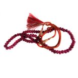 A melon cut ruby necklace,  with two colour silk cord tie