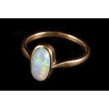 An opal ring,  the central oval stone rub over set, the shank unmarked, finger size M/N