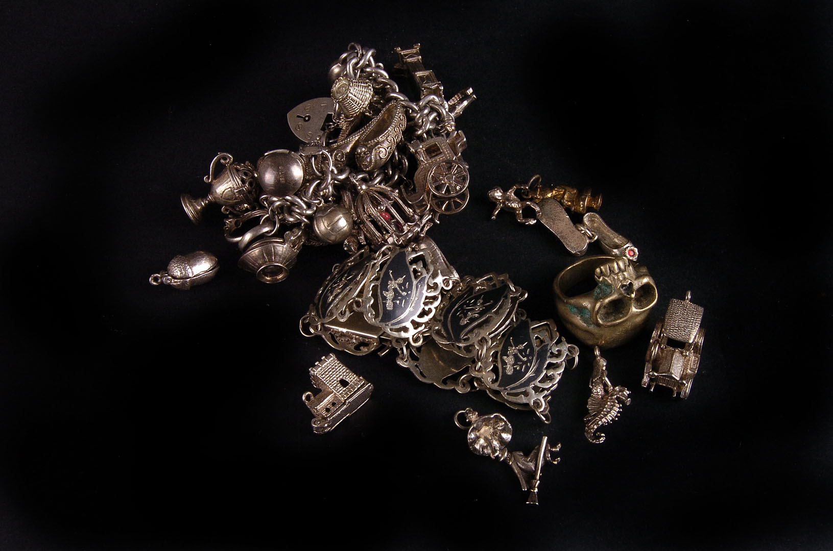 A 1970s silver curb link charm bracelet,  suspended with numerous charms, some loose, together