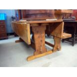 A late 20th century elm bespoke drop leaf dining table, with trestle board ends and pegged bar