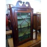 A George III mahogany corner cupboard, wall mounted and with broken swan neck pediment over a triple