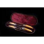 A Victorian cased carving set,  having whale tooth handles, with silver collar mounts, and steel