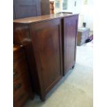 A George III mahogany press cupboard, with two panel doors opening to reveal press slides, on turned