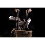 A set of golf clubs, including irons, woods, putters and wedge, in a fabric golf bag