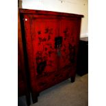 A Chinese red lacquer cabinet, the doors hand decorated with rock and peony designs, and with fan