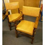 A pair of oak Puritan Revival arm chairs, with stuff over leatherette seats 90cm high, plus an