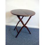 A Victorian mahogany coaching table, the circular top on folding curved supports