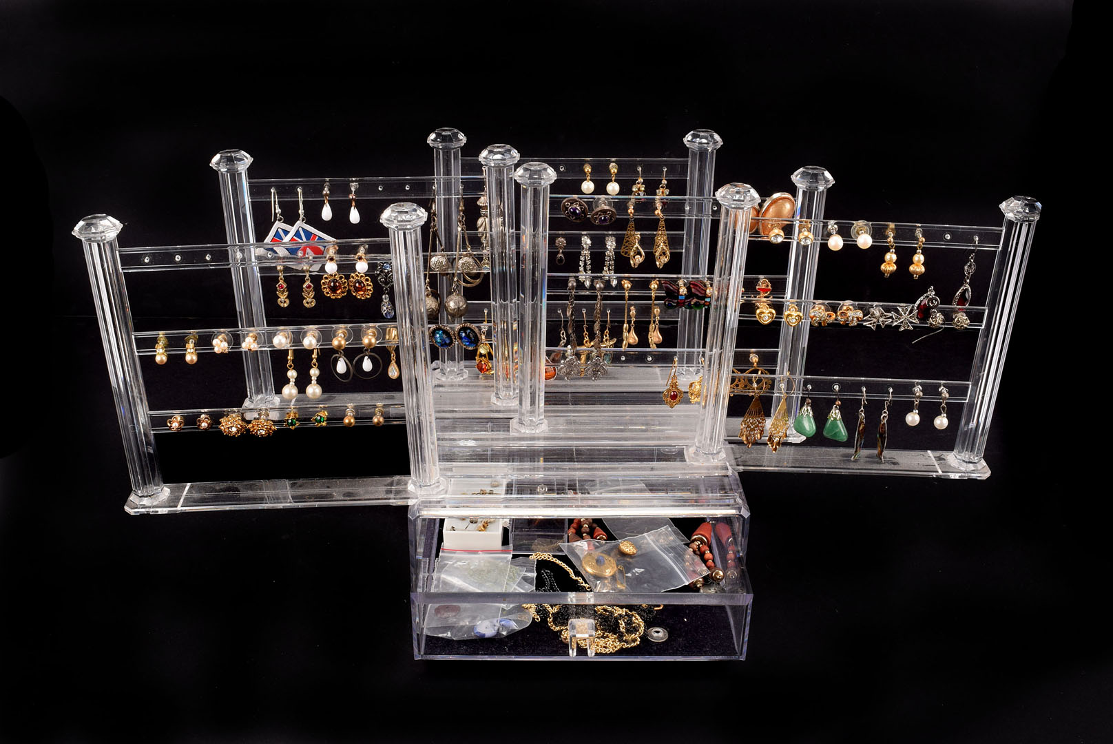 A collection of costume ear studs and pendants, various designs, in a Perspex display case