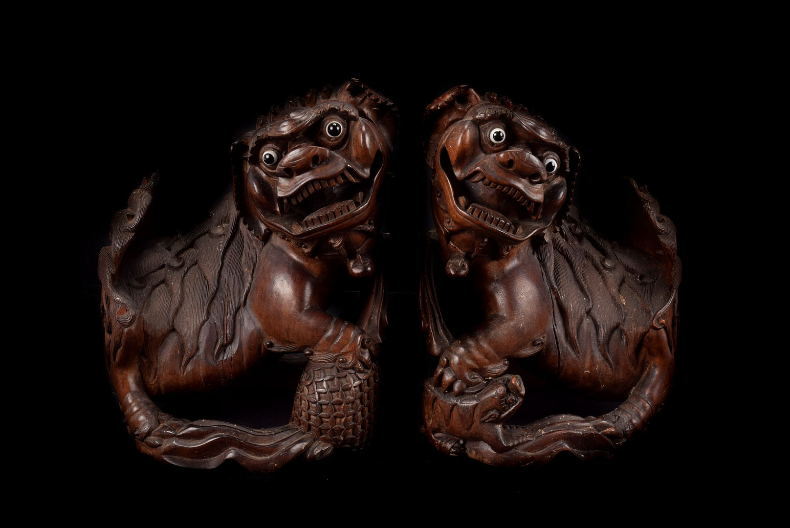 A pair of late 19th century Chinese hardwood temple dogs, the well carved Fo dogs with glass bead