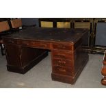 An Edwardian red walnut or mahogany partners desk, having leather top, on pedastals with three