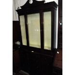 A modern mahogany bookcase cabinet, the upper glazed section having broken pediment, supported on