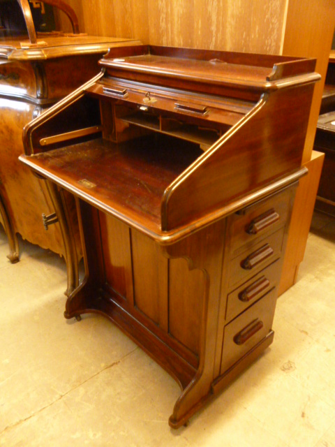 An early 20th century mahogany Lebus roll top desk, the tambour opening to reveal pigeon holes,