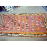 A vintage Persian Kilim carpet, the long red rug with red ground and geometric medallions, some