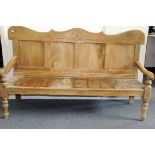 A large Victorian pine settle, with carved top rail having moulded motif, damages to arms and