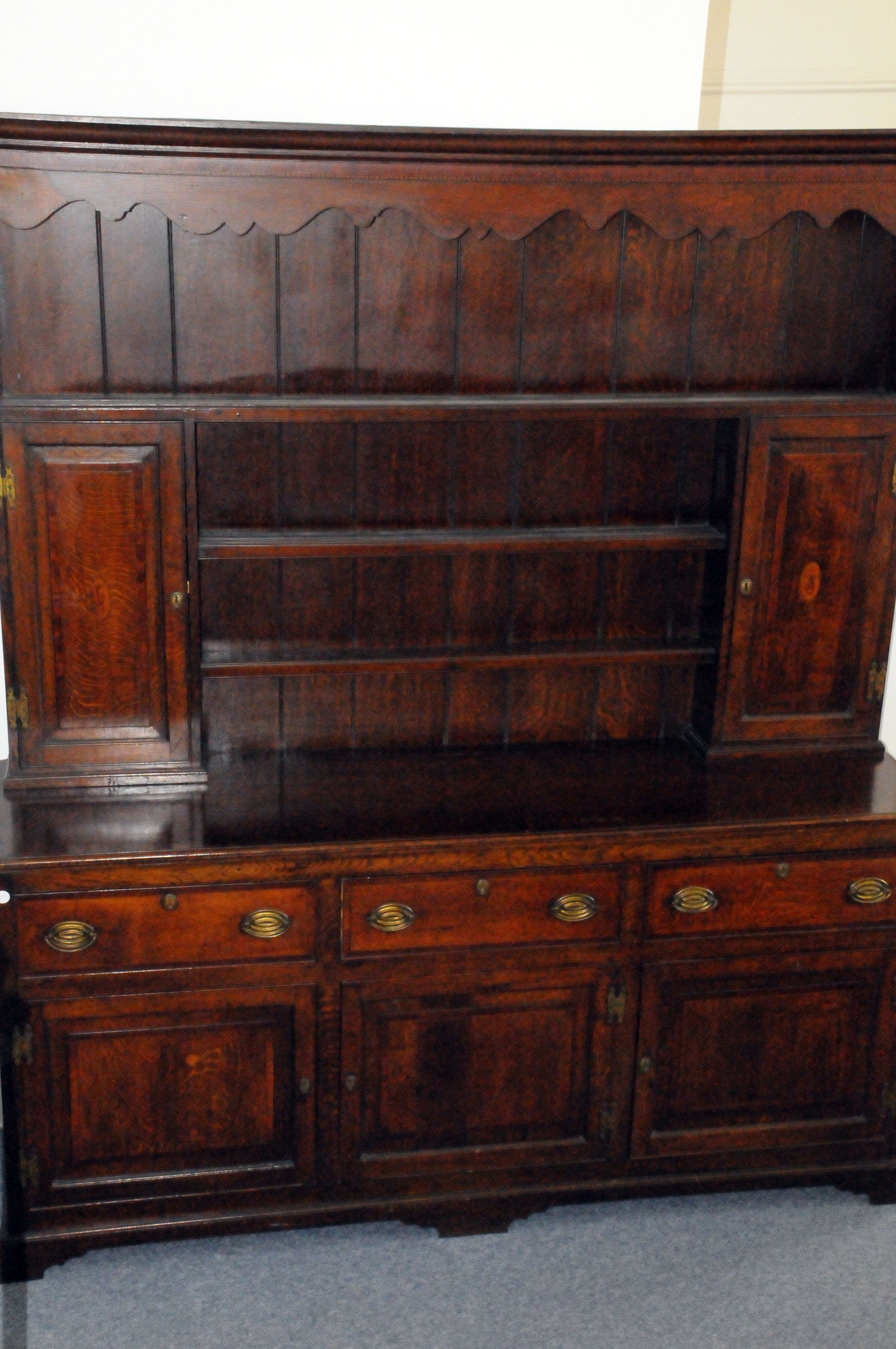 A George III period oak sideboard dresser, the base with three doors and drawers below shelved upper