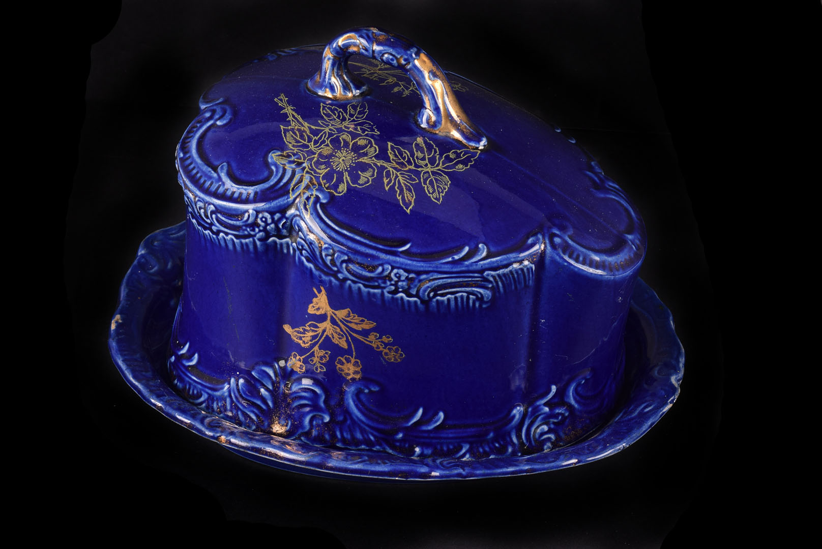 An Edwardian pottery cheese dish and cover, in royal blue glaze and heightened in gilt floral