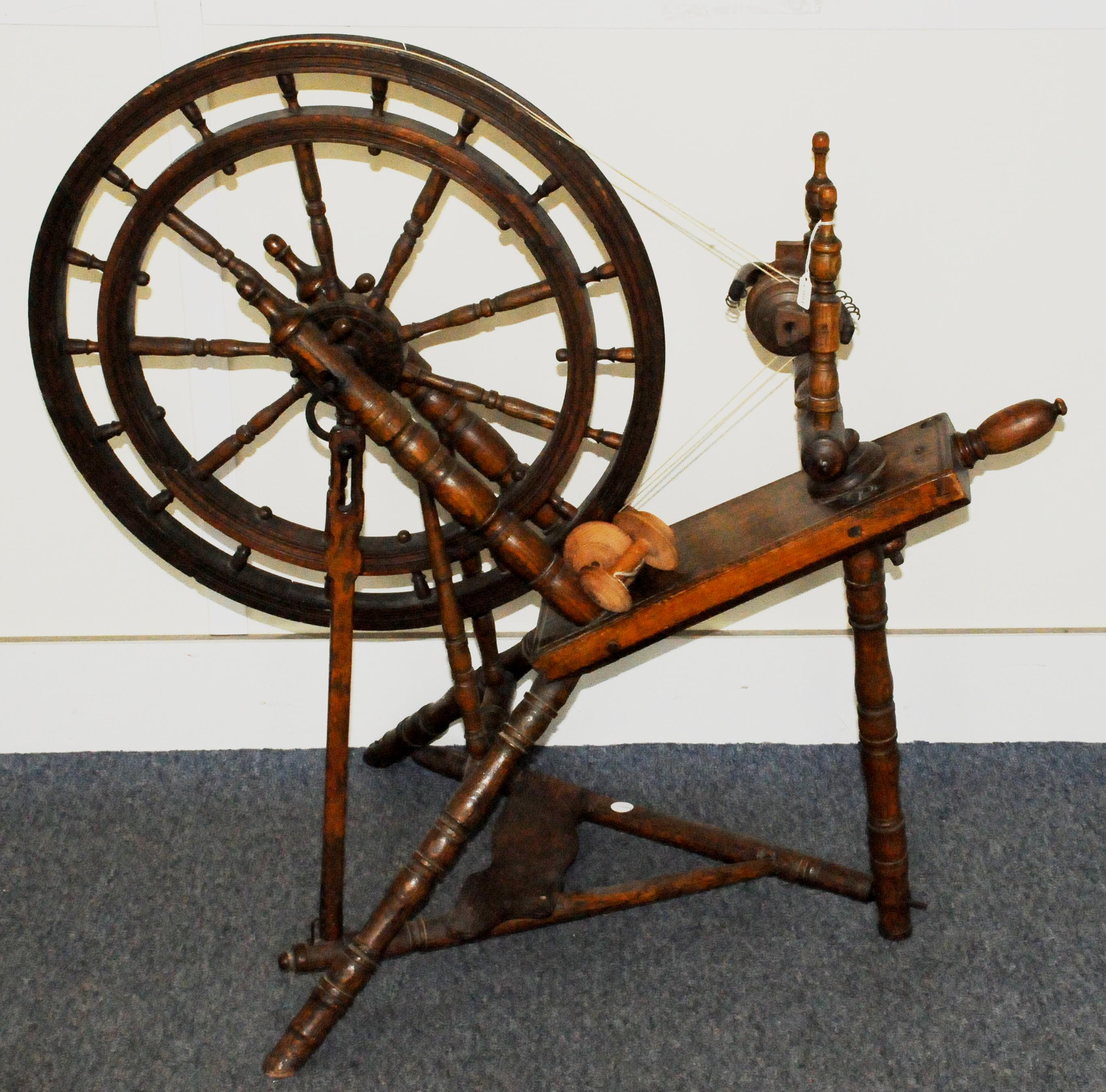 An antique hardwood spinning wheel, with cast iron fittings, overall in fair condition but some