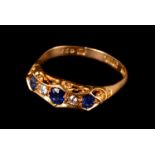 An Edwardian 18ct gold five stone ring, having three light blue sapphires and two old cuts