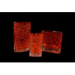 Three tangerine nail head bowed shaped glass vases, all having textured design to front and back,