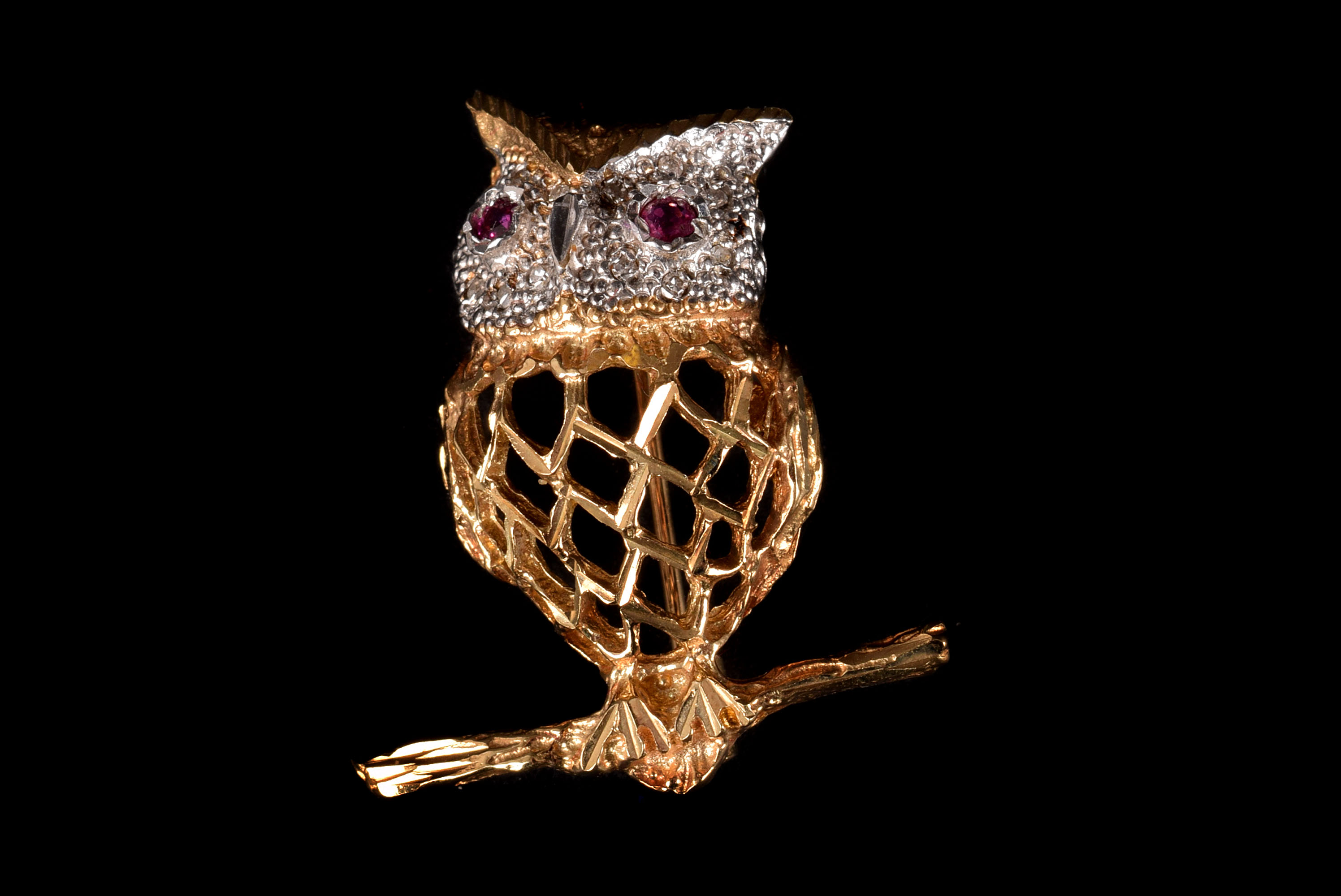 A modern yellow metal and gem set owl brooch, having red stone eyes in white metal with clear stones