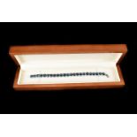 A modern 9ct gold and gem set line bracelet, the white gold bracelet set with a row of blue