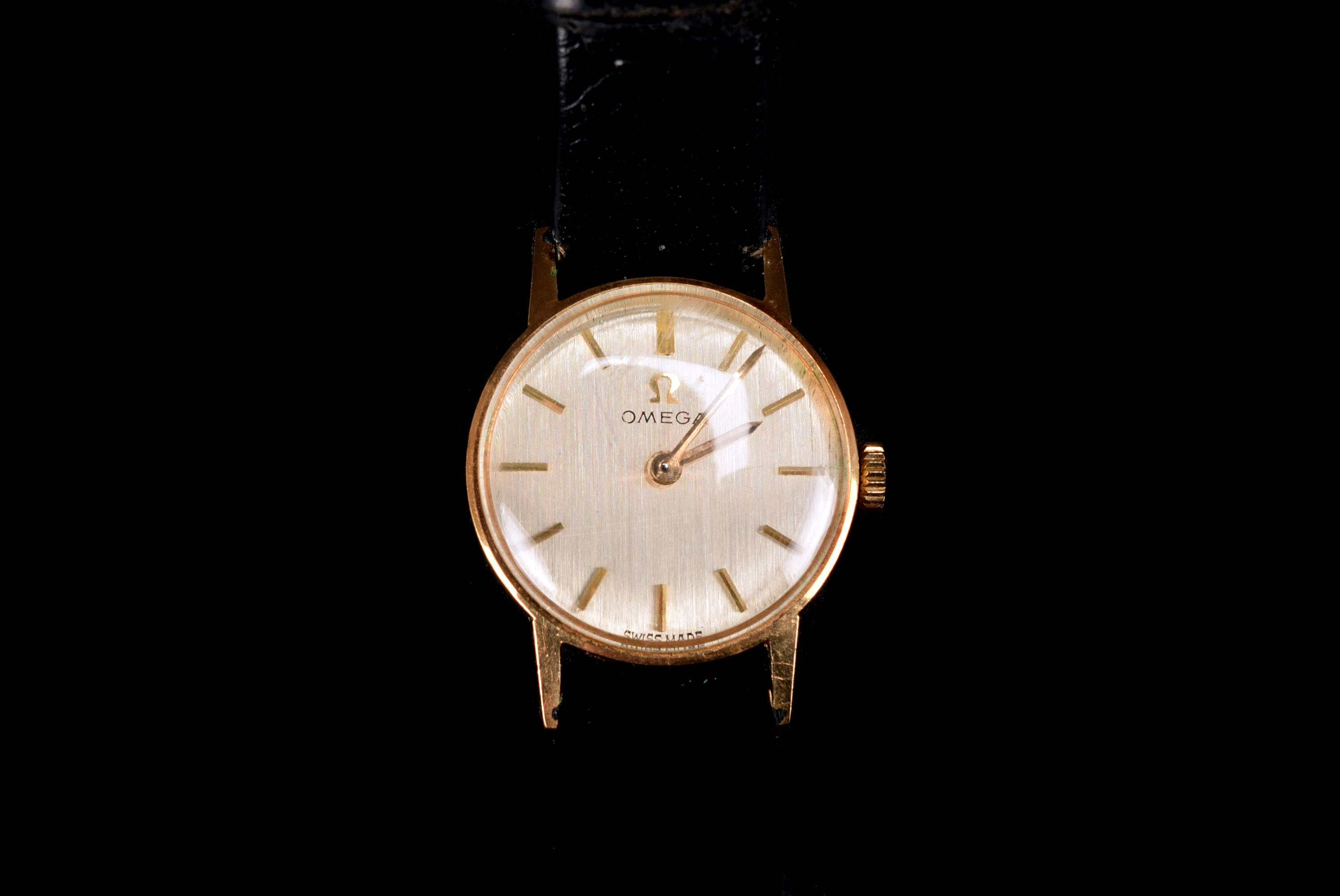 A 1970s Omega lady's wristwatch, the gold coloured circular case, supported on a black leather