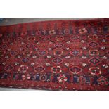 A red ground Turkomen carpet, with multiple central floral medallions, surrounded by a blue ground