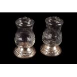A pair of cut glass table peppers, the Quaker silver Co white metal bases supporting engraved