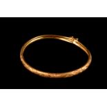 A modern Middle Eastern yellow metal bangle, having satin finish with heart shaped engraved designs,