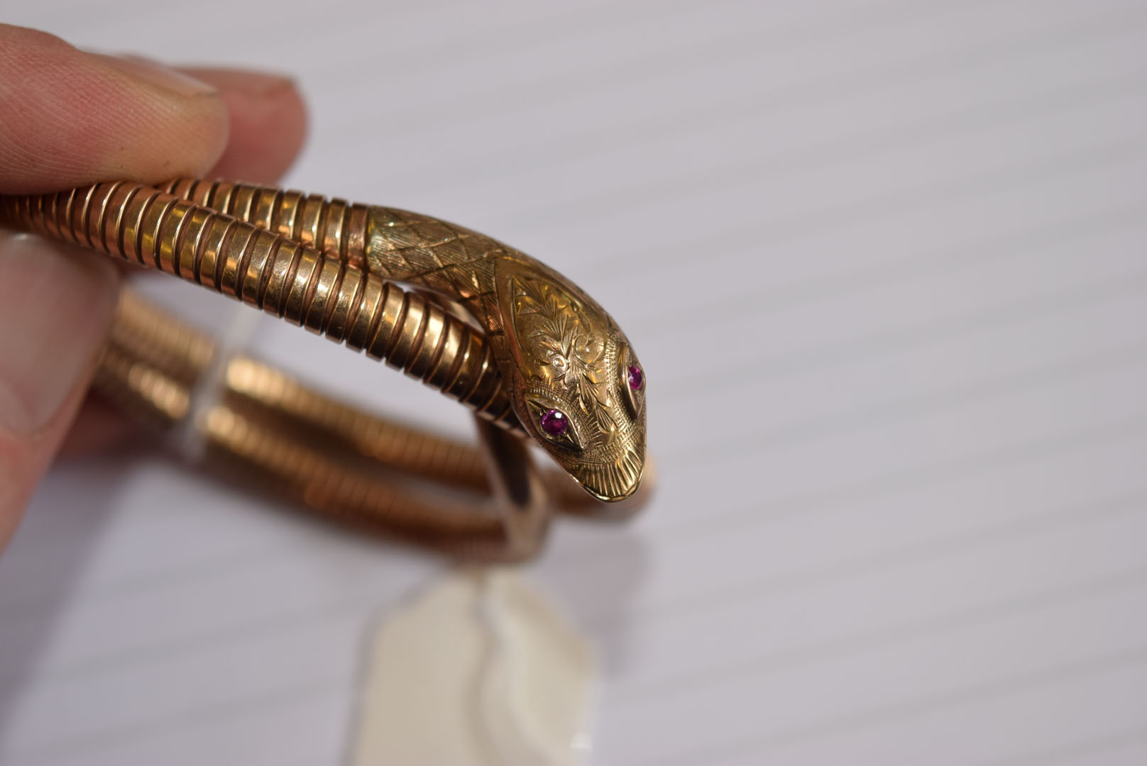 A 9ct gold snake bangle, the stretchy body leading to a decoratingly engraved head, having synthetic - Image 7 of 7