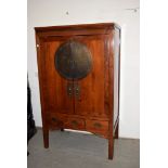 A Chinese Qing dynasty elm moon cabinet, or betrothal cabinet, the double doors with circular plaque