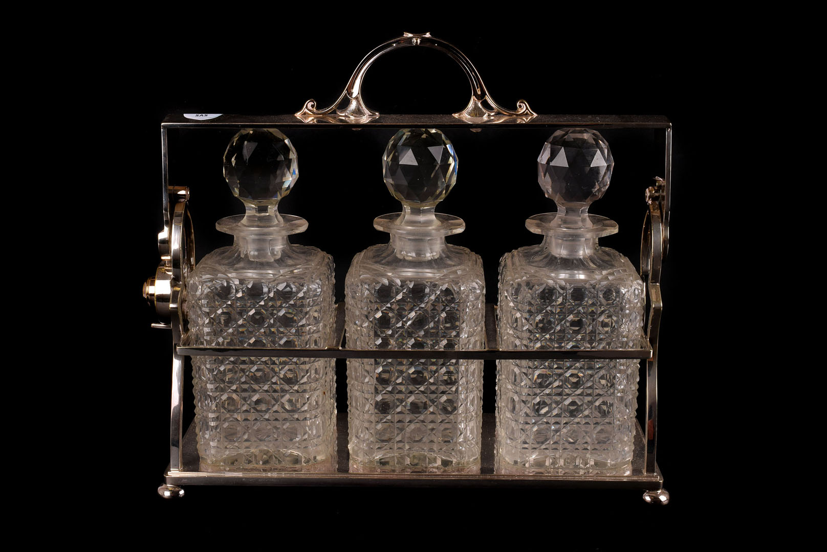 A silver plated tantalus, having three decorative cut glass decanters and stoppers (4)