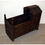 A 19th century oak child's rocking crib, having carved panels with floral decoration