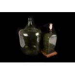 A large green carboy, plus a 19th century square based green glass bottle as a lamp base, a spirit