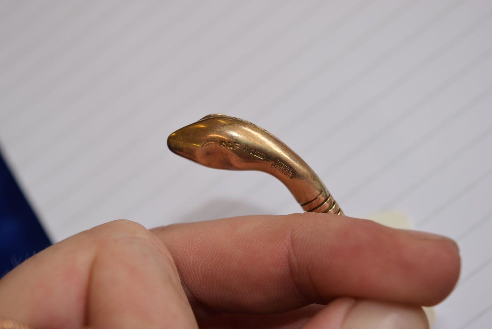 A 9ct gold snake bangle, the stretchy body leading to a decoratingly engraved head, having synthetic - Image 5 of 7