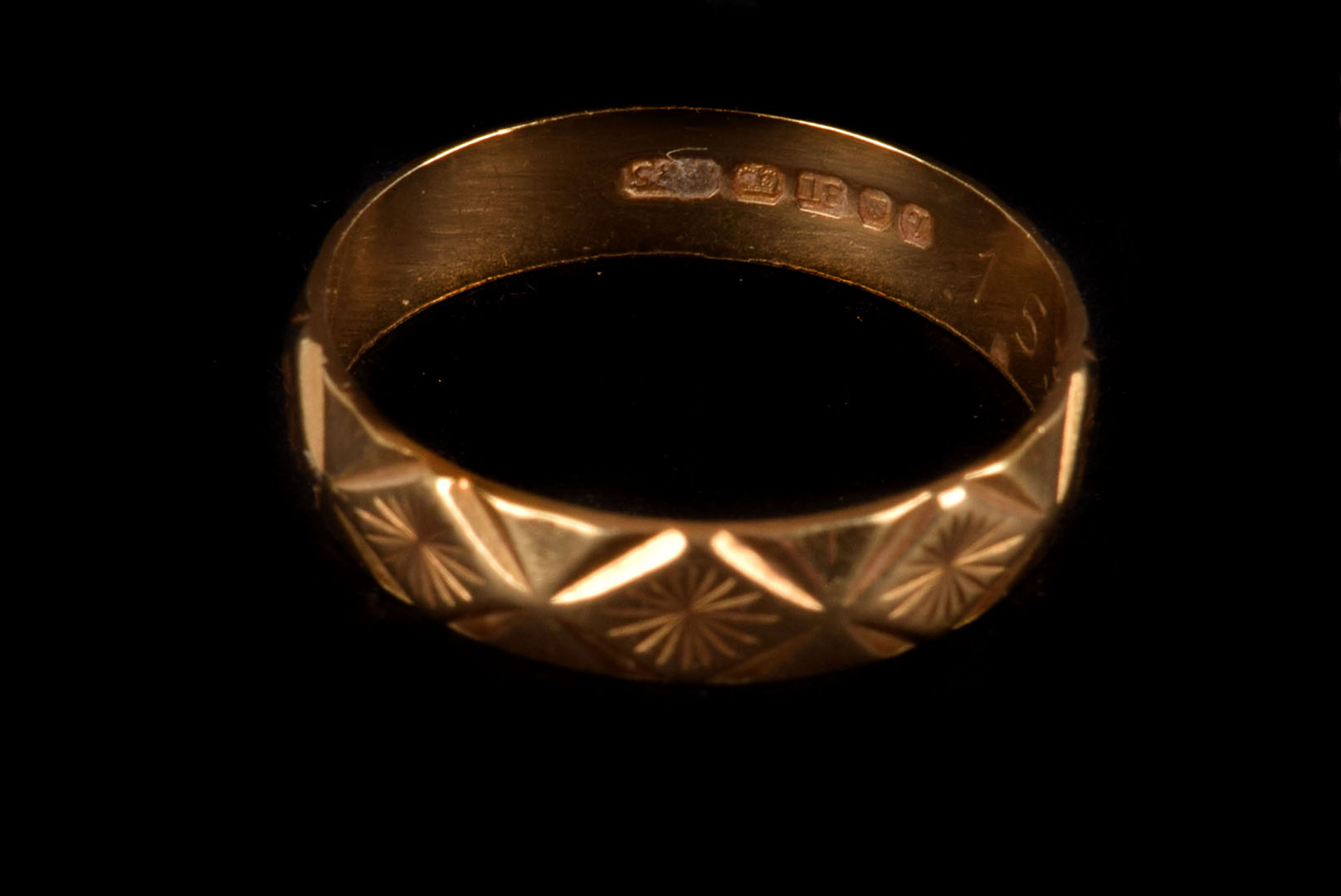 An 18ct gold band, having repeatative geometric engraved design, approx 2.8g