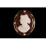 A Victorian gold and sardonyx cameo brooch, the sardonyx cameo of a well dressed young lady set in a