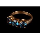 A modern 9ct gold and gem set dress ring, the three round cut blue stones, set in 9ct gold four claw