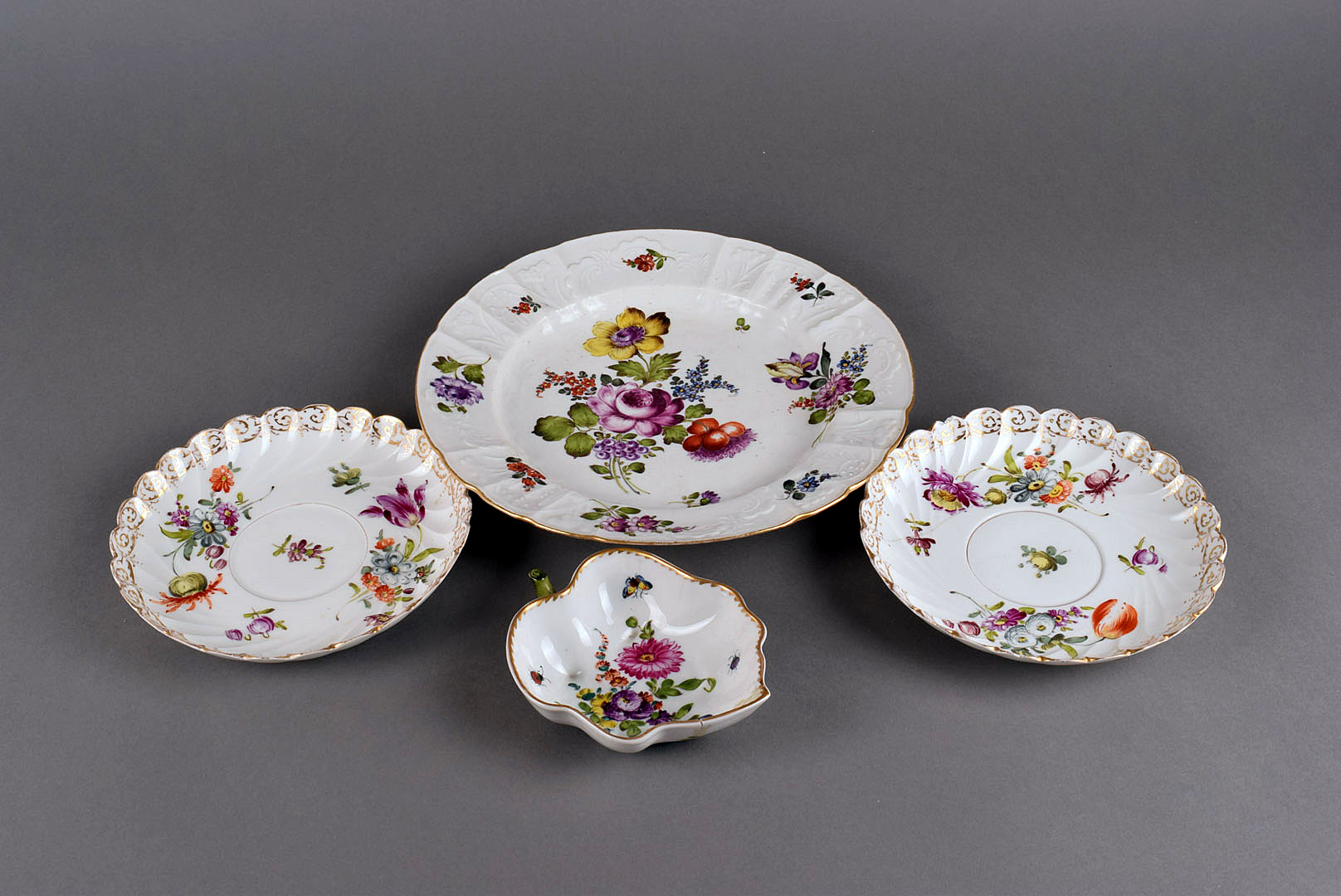 A small assortment of Dresden porcelain, comprising a plate, four large saucers and a leaf shaped